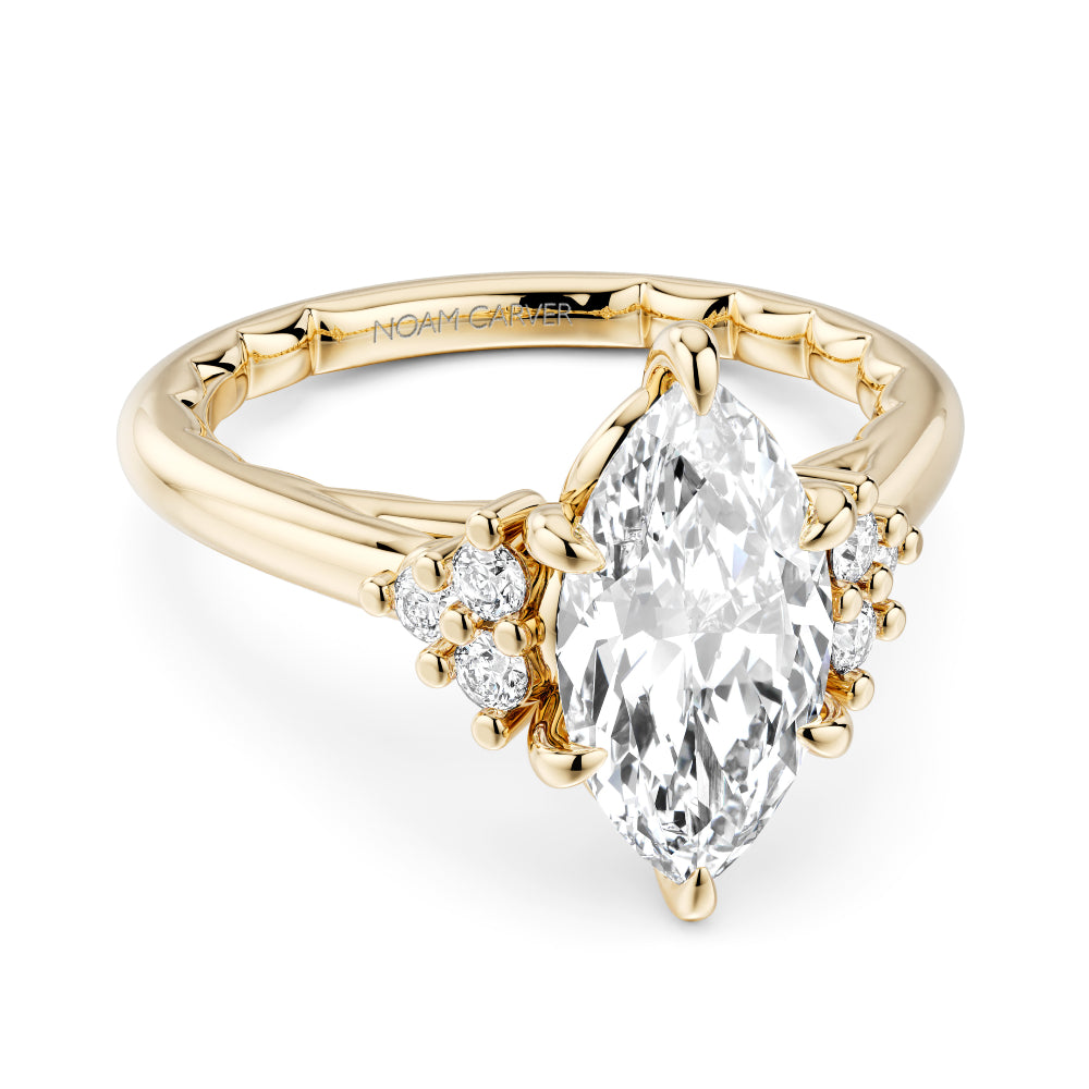 Gold Noam Carver ring with a large marquise diamond and smaller diamonds on a white background