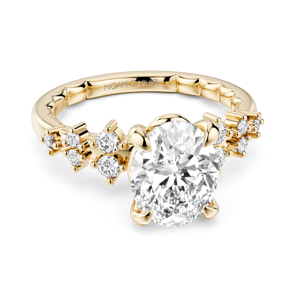 Gold Noam Carver ring with a large oval diamond center and smaller round diamond sides on a white background