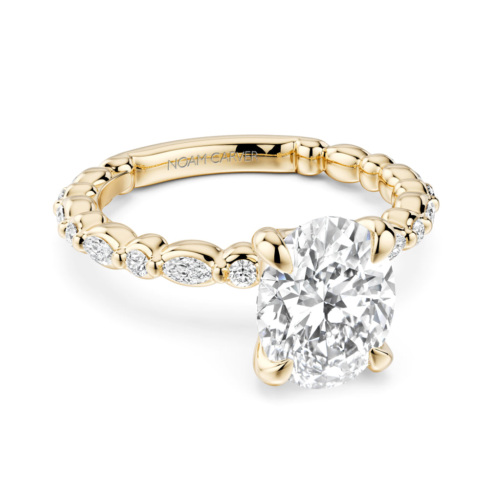 Gold Noam Carver ring with a large oval diamond center and smaller round/marquise diamond sides on a white background