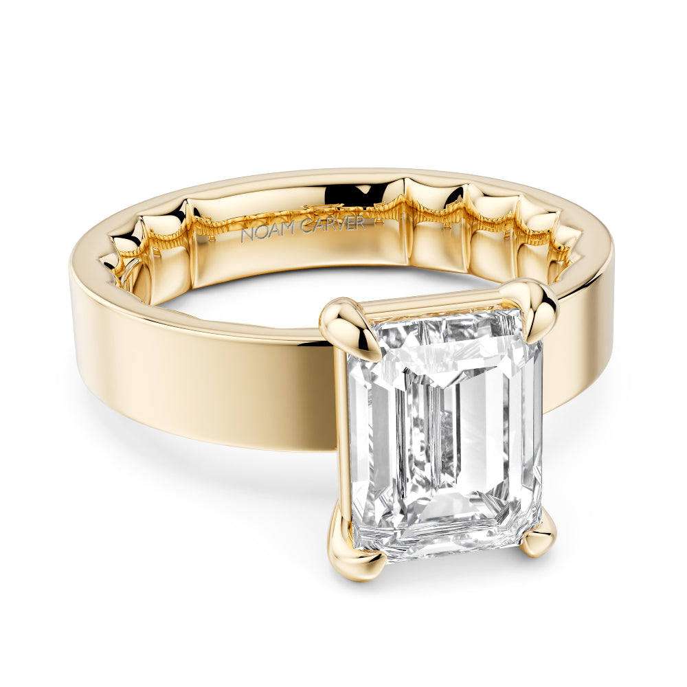 Wide band gold ring with a large emerald cut diamond on a white background