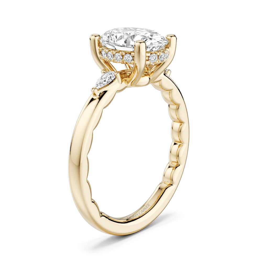 Gold Noam Carver ring with a large oval diamond center and smaller pear shape diamond sides on a white background