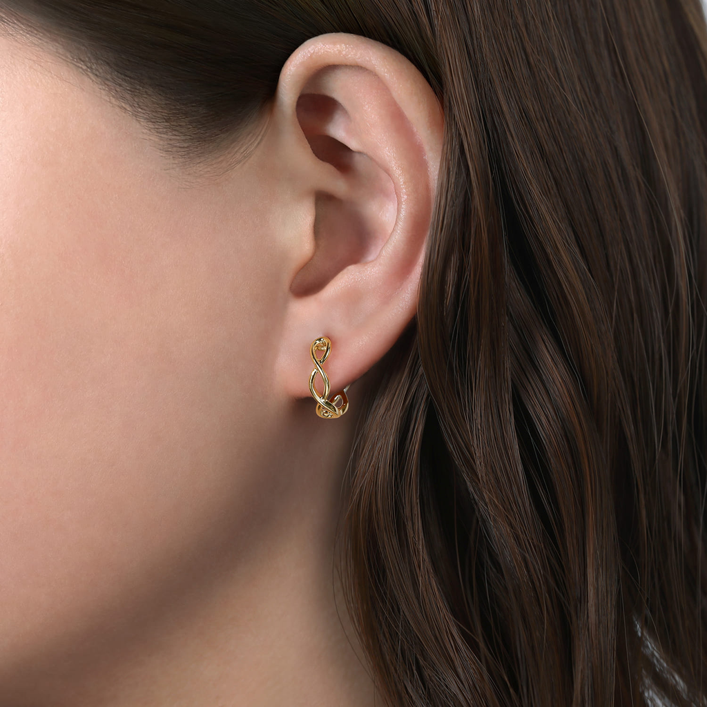 Close-up of a person wearing a gold earring with dark hair.
