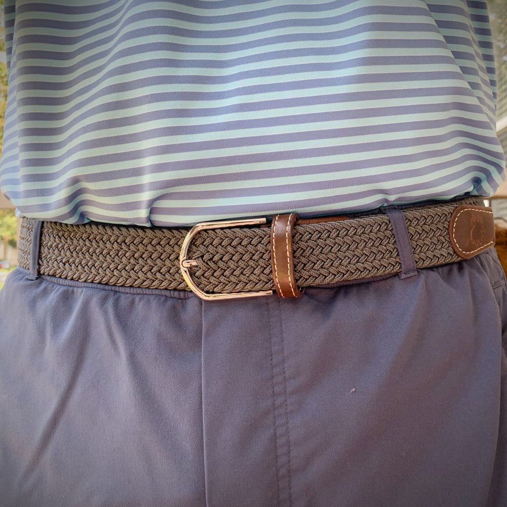 person wearing beige/brown woven belt outdoors. 