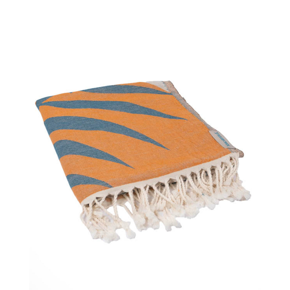 Folded orange, blue and brown beach towel with parrot and leaf design and a white tassel edge white on a white background.