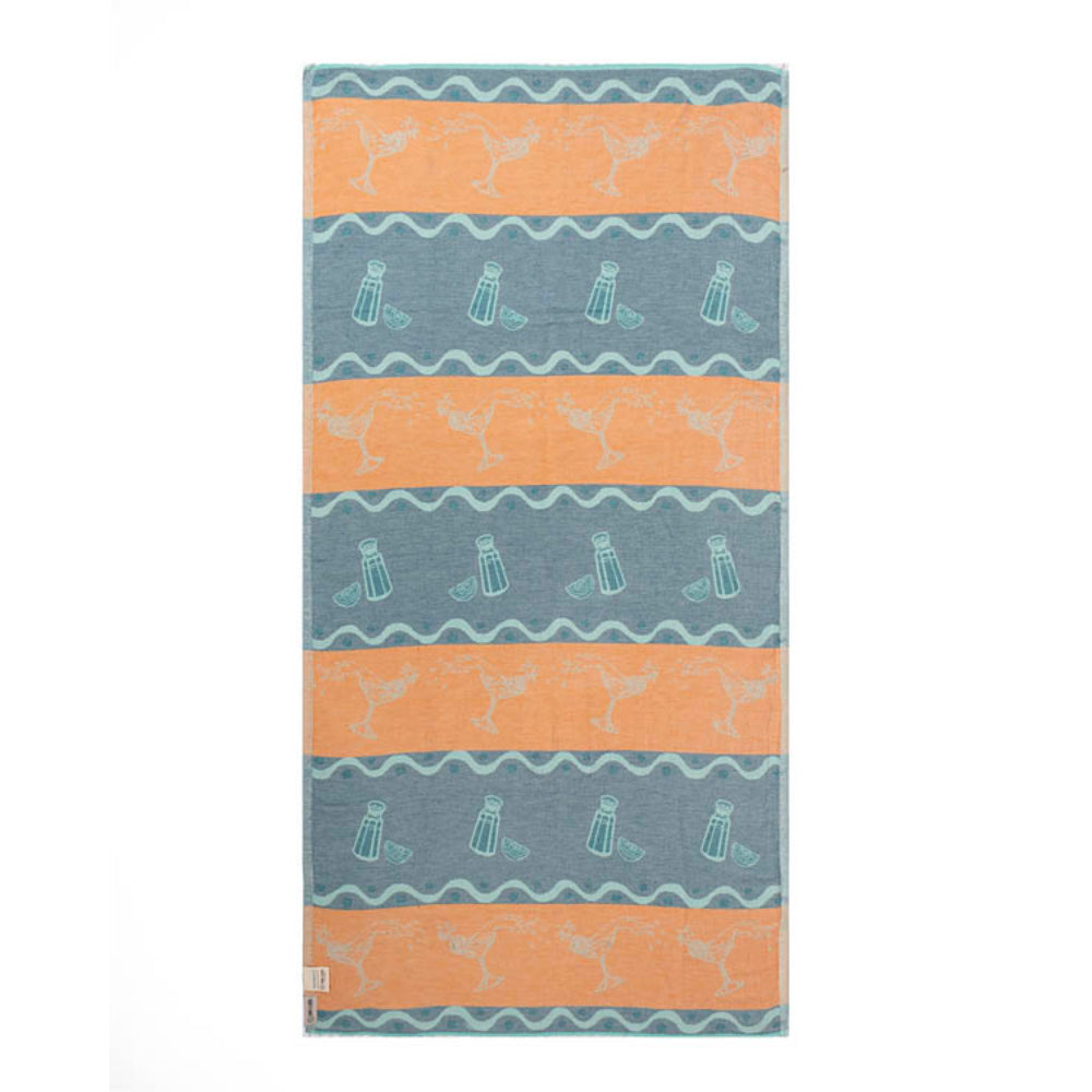 Side two of a blue beach towel with beach-themed design featuring martini glasses and wavy lines and white tessal edges on a blue and orange background.
