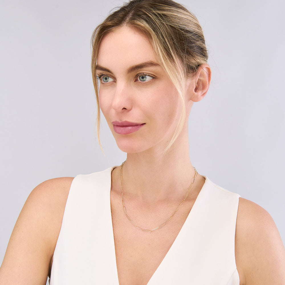 Woman wearing a Gold paperclip chain necklace on a white background