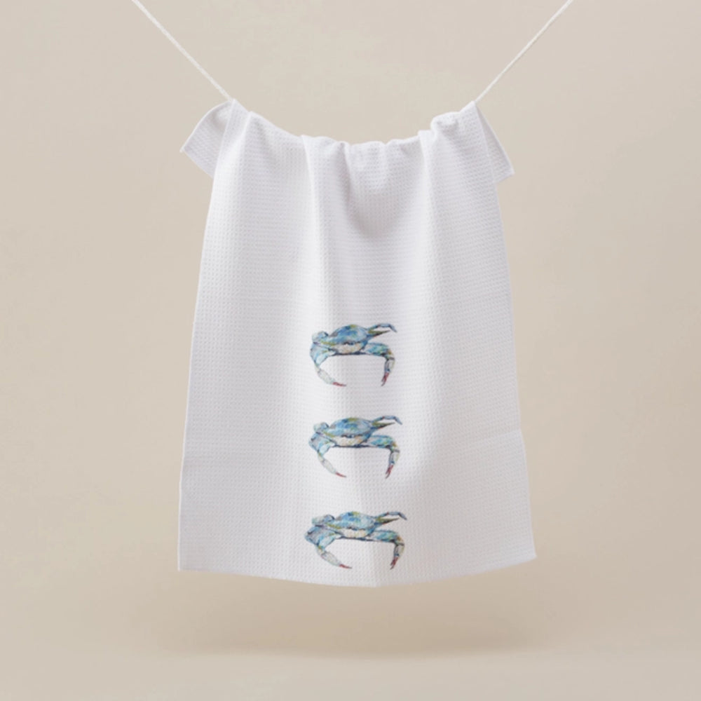 White towel with blue crab designs hanging on a line against a beige background
