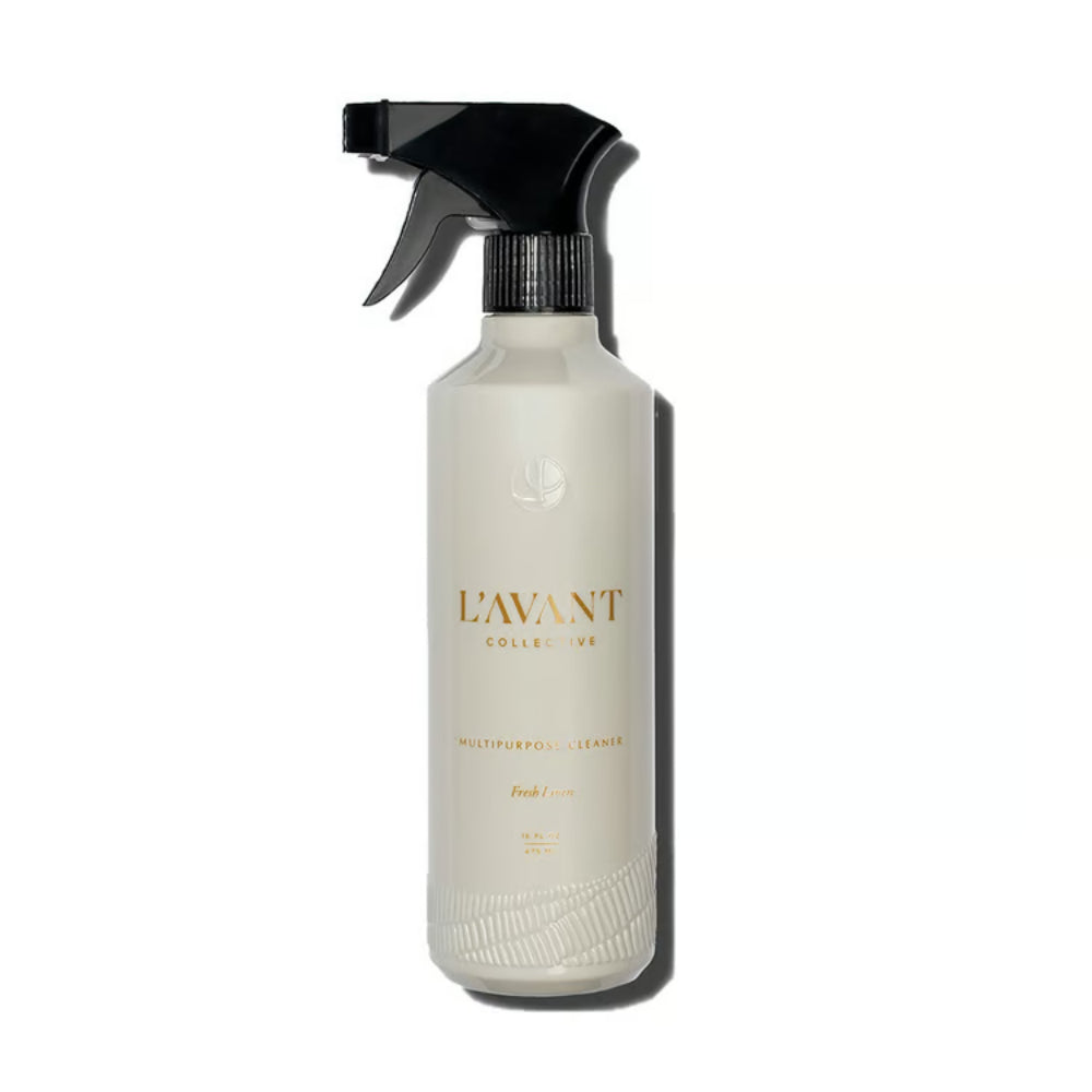 A bottle of L'Avant Collective Fresh Lemon Multipurpose Cleaner with a frosted off-white body, a black spray trigger top, and gold lettering, set against a plain white background with a soft shadow.