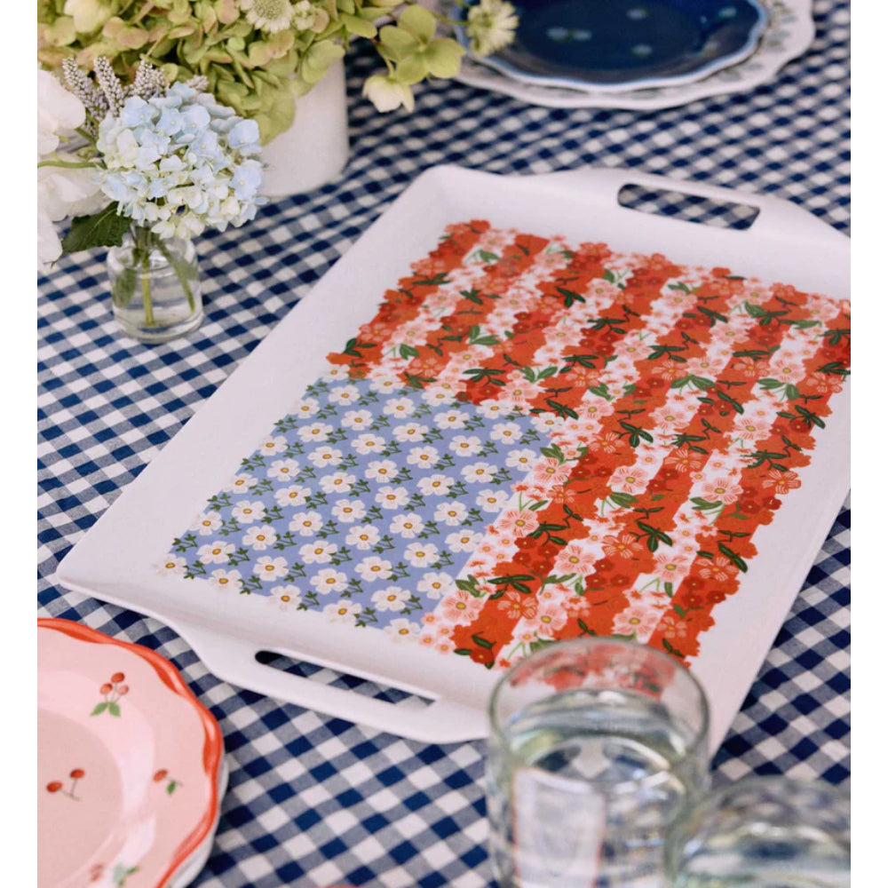 Decorative American flag floral tray with floral pattern on a checkered tablecloth with flowers and other table items.