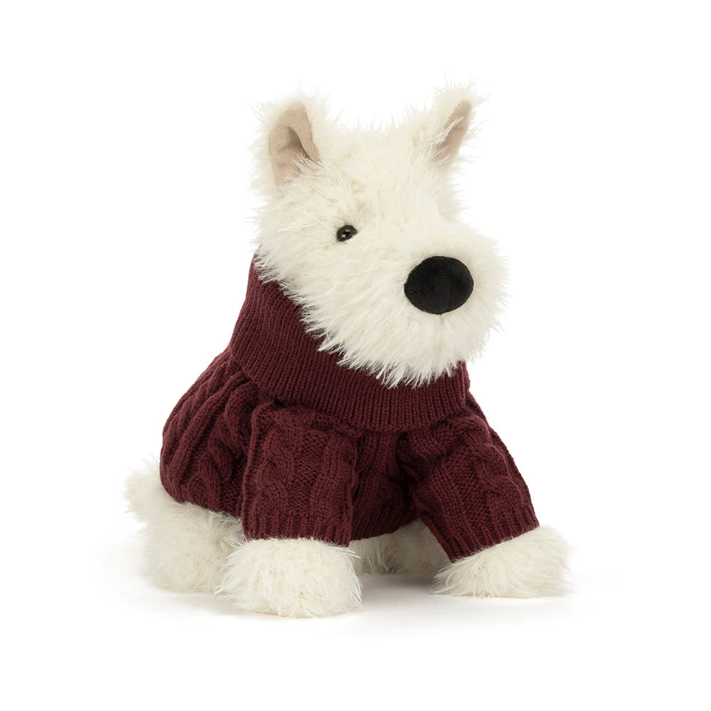 A stuffed plush dog in a red jumper sweater outfit on a white background. 