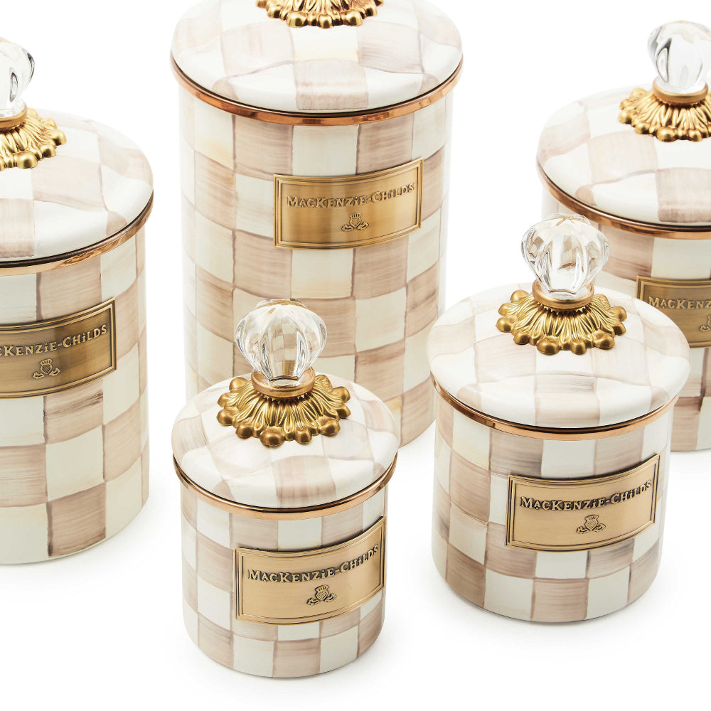 A close of up of different sized decorative jars with a mocha checkered pattern and gold accents on a white backround. 