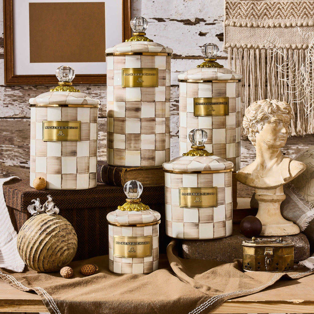 Decorative jars with a mocha checkered pattern and gold accents on a with tan decor items in a decorative setting.