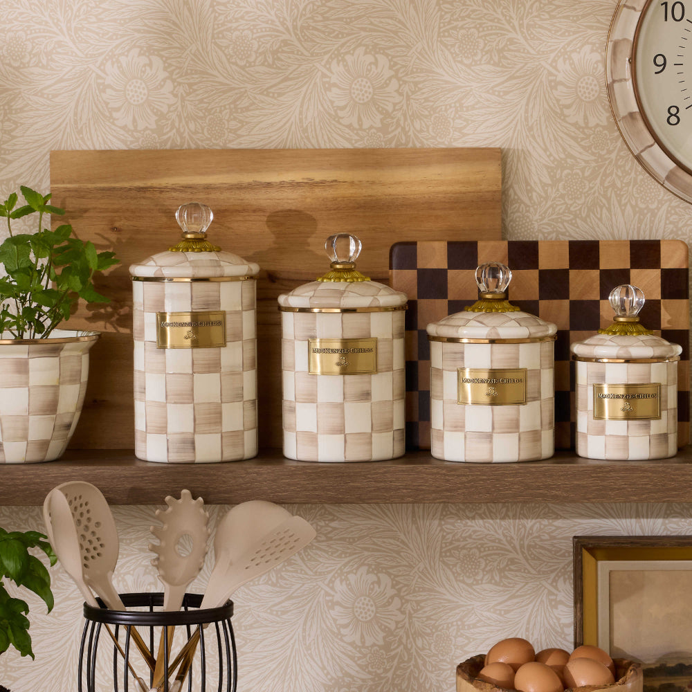 Decorative jars with a mocha checkered pattern and gold accents on a on a shelf in a kichen in  decorative setting.