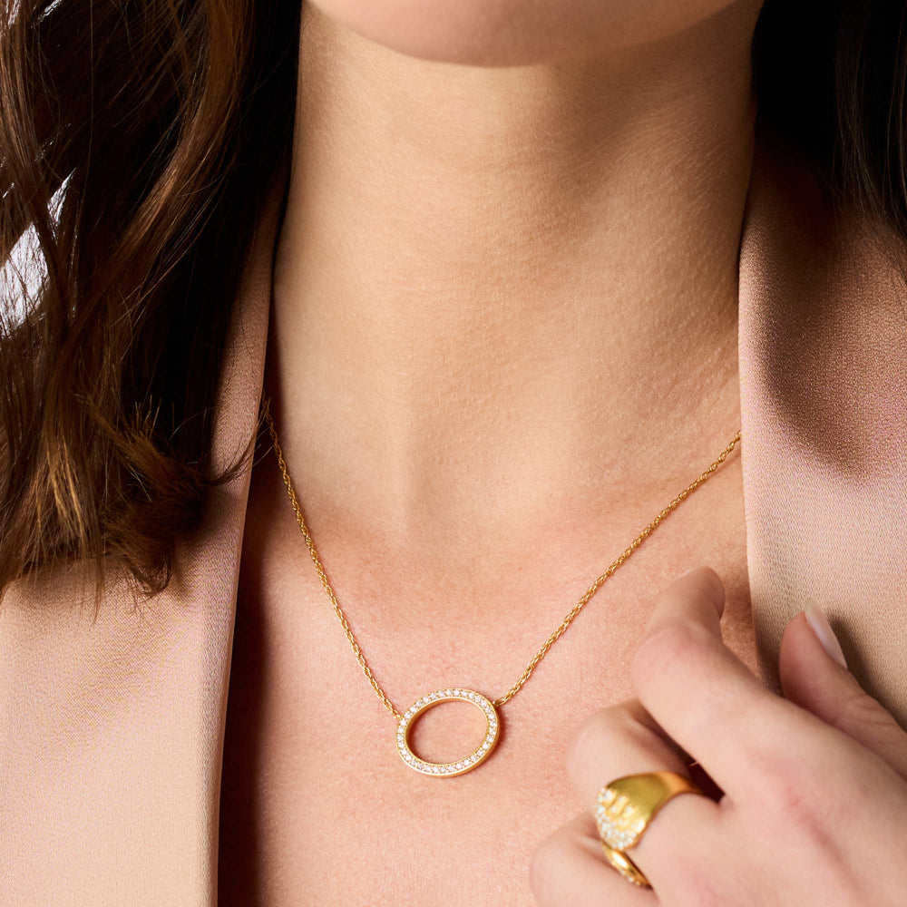 Gold necklace with a pendant worn by a person, close-up view.