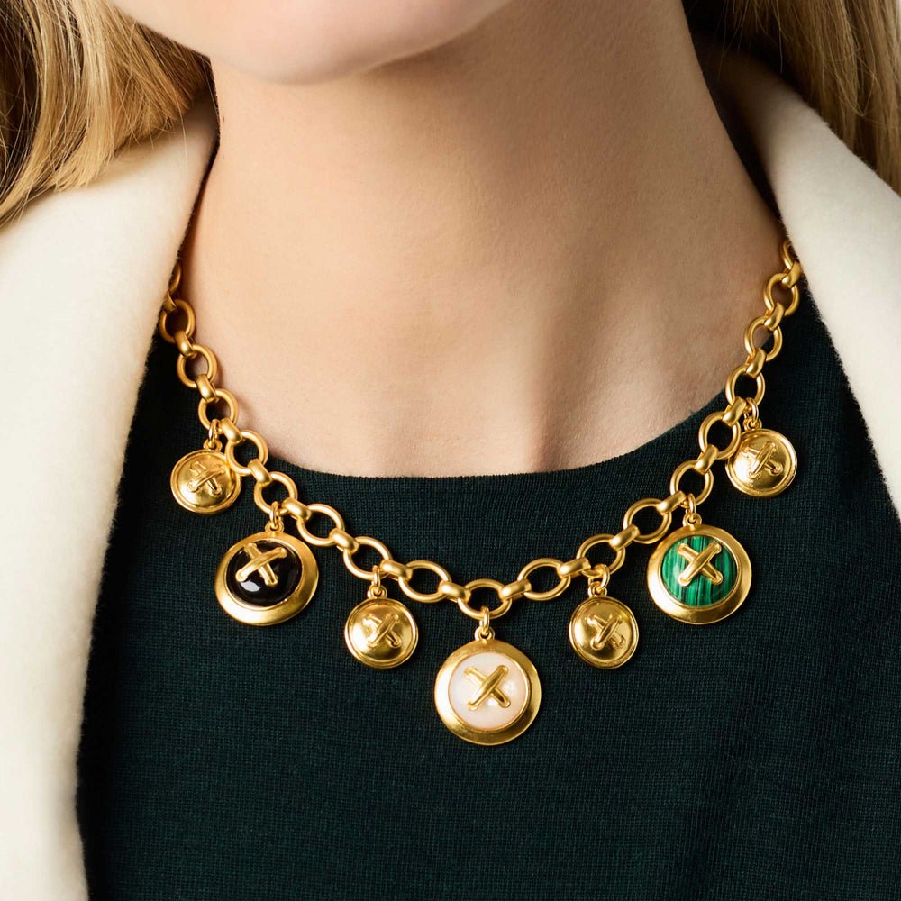 Gold necklace with various pendants worn by a person