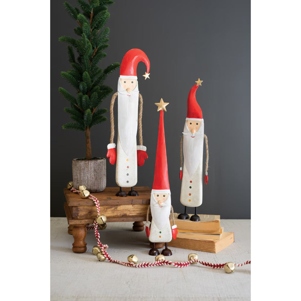 Wooden Santa Claus figures with red hats and white bodies on a wooden stand against a dark wall.