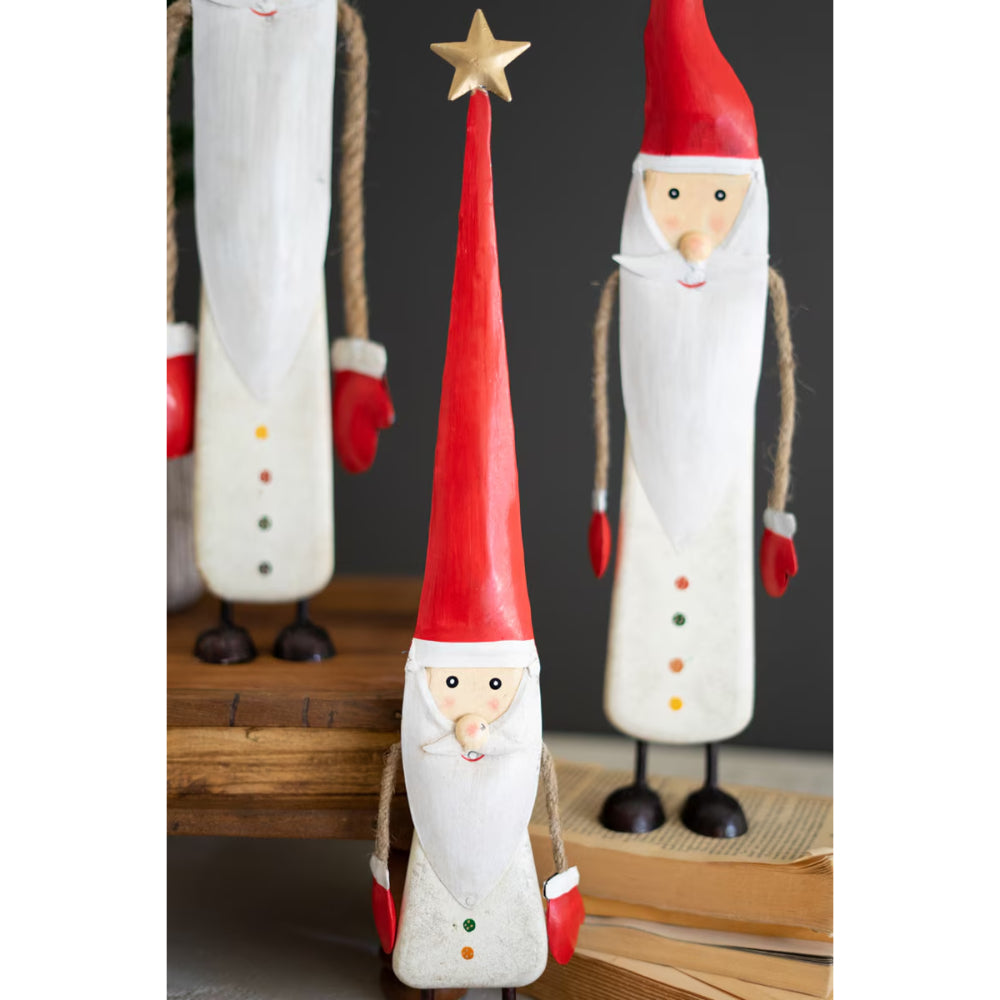 Wooden Santa Claus figurines with red hats and white bodies on a wooden surface.