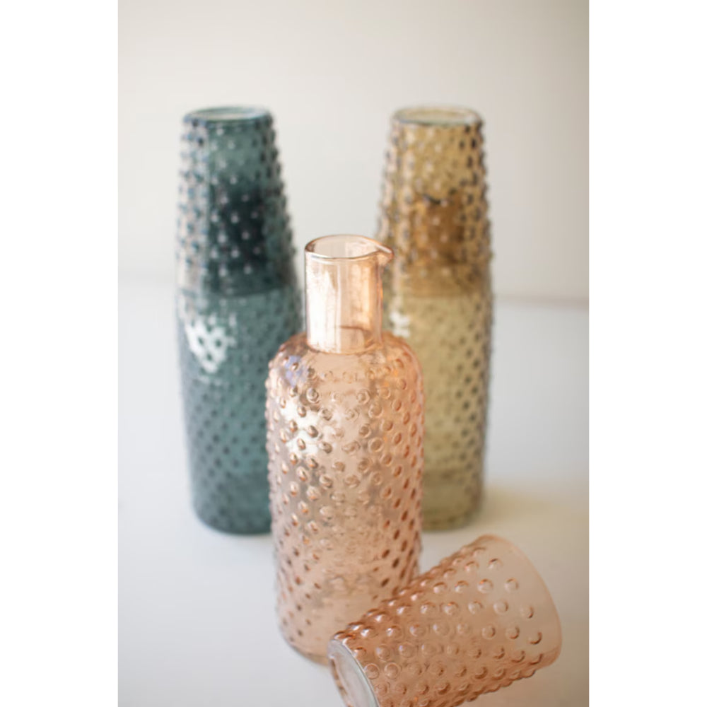 Three textured glass vases in green, gold, and rose gold on a light background