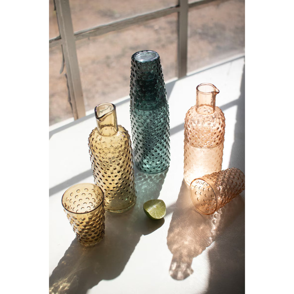 Set of textured glass bottles on a light surface with a blurred outdoor background