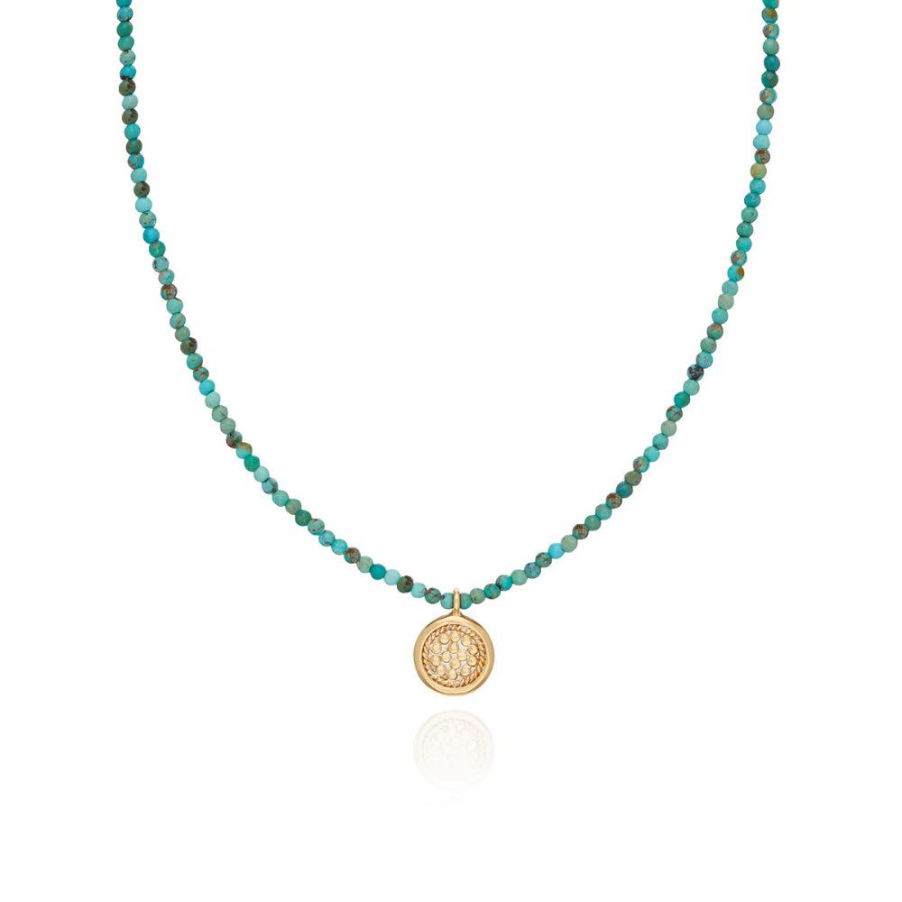 Necklace with turquoise beads and a gold pendant on a white background