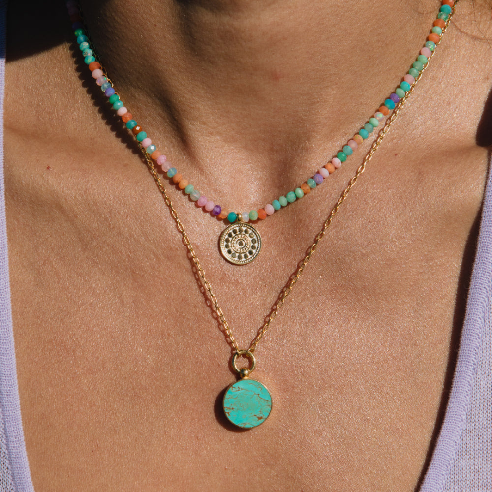 Woman wearing Frida Beaded necklace along with other necklace with green pendant 