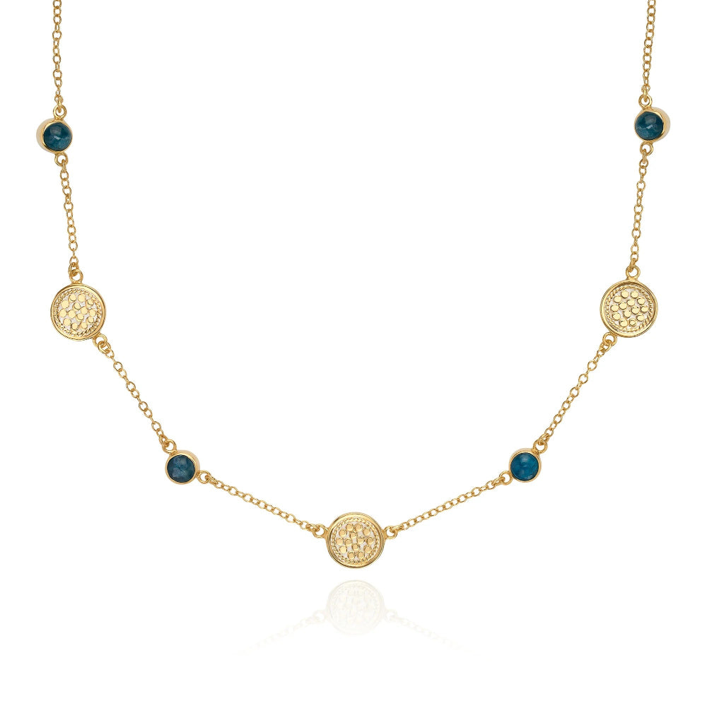 A gold chain necklace featuring five ornate circular gold medallions and five small round dark blue gemstone accents