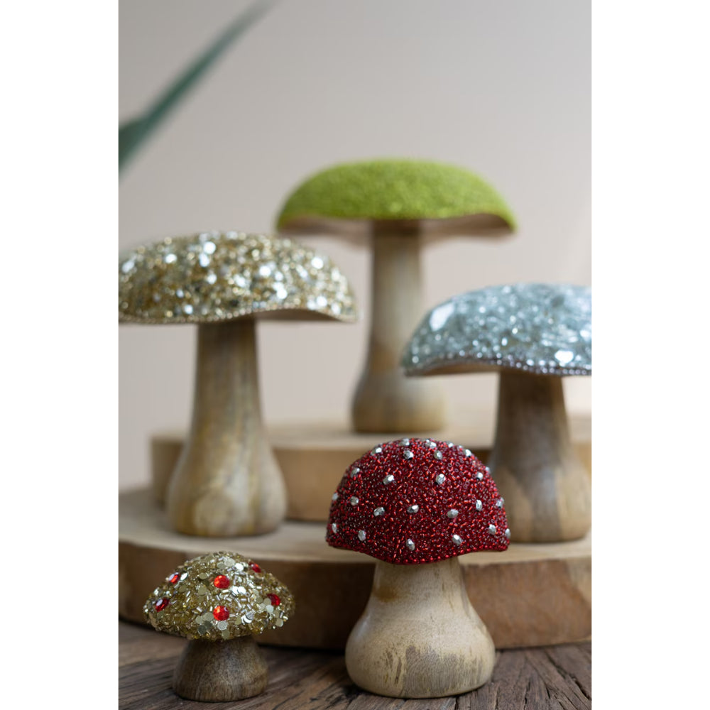 Decorative mushroom figurines with gemstone embellishments on a wooden surface.