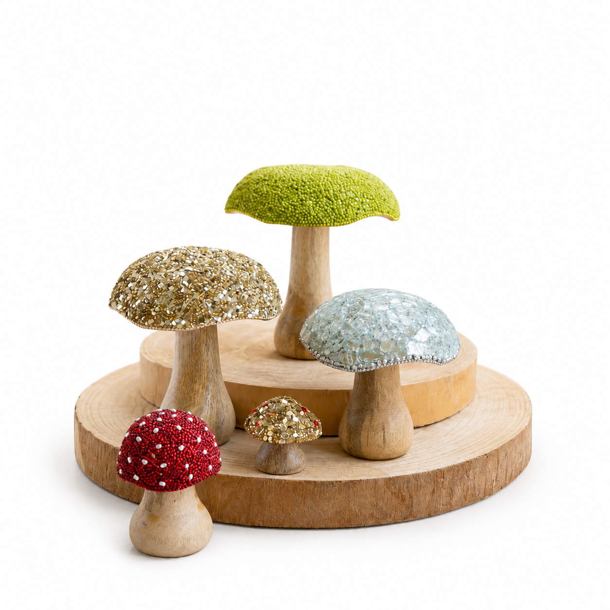 A set of decorative glittery mushroom figurines in red, gold, green, and light blue, arranged on a round wooden display stand against a white background.