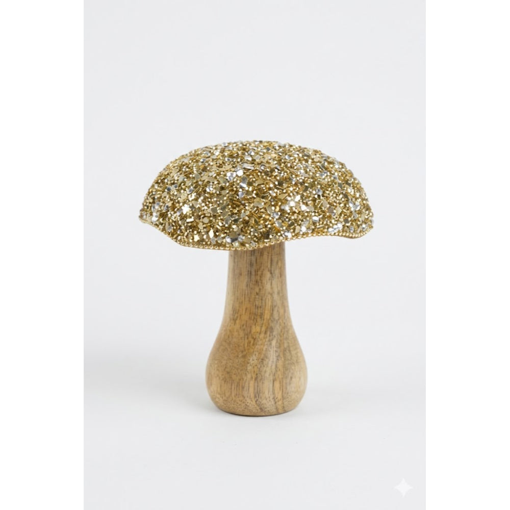 Decorative mushroom with gold glittery cap and wooden base on a white background