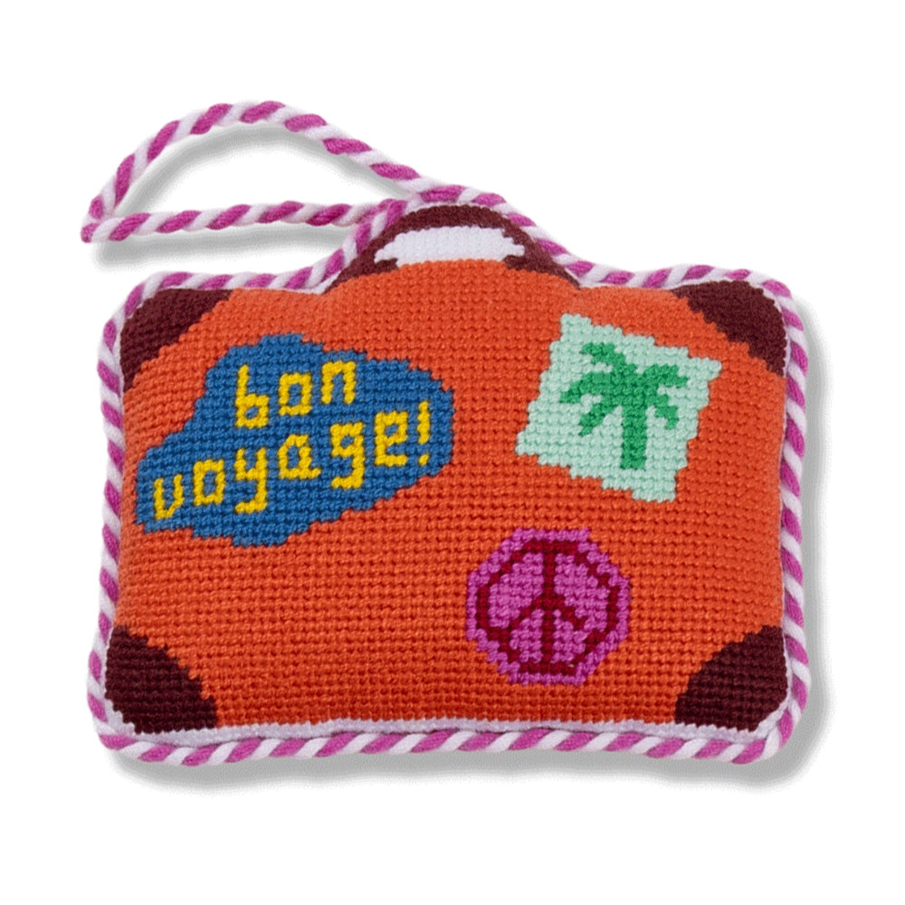 Small needlepoint suitcase ornament with 'bon voyage!' text and travel-themed designs on a white background.
