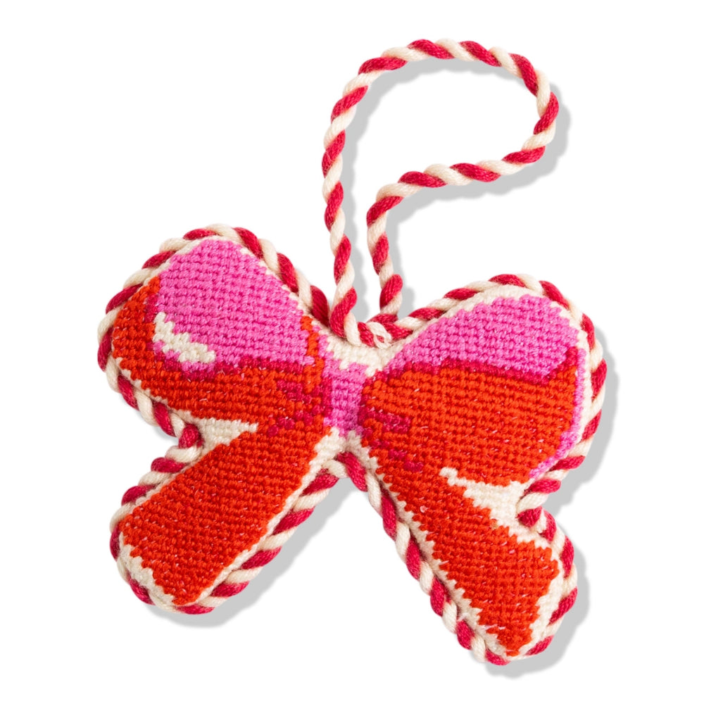 A decorative embroidered bow ornament with red, pink, and orange stitched sections, finished with a red-and-white twisted rope loop at the top, shown on a plain white background.