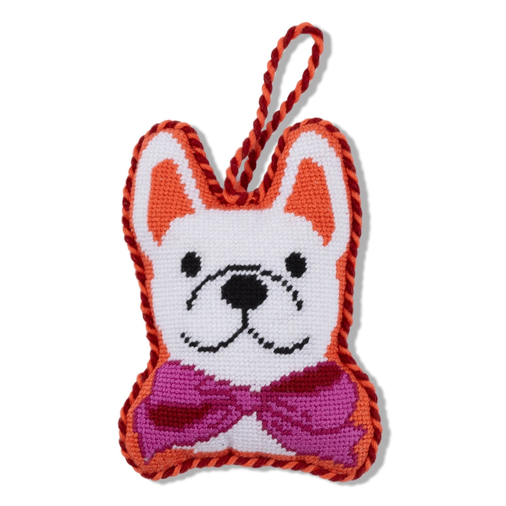 A needlepoint french bulldog oranament with a red and orange edge with a pink bow on a white backround. 