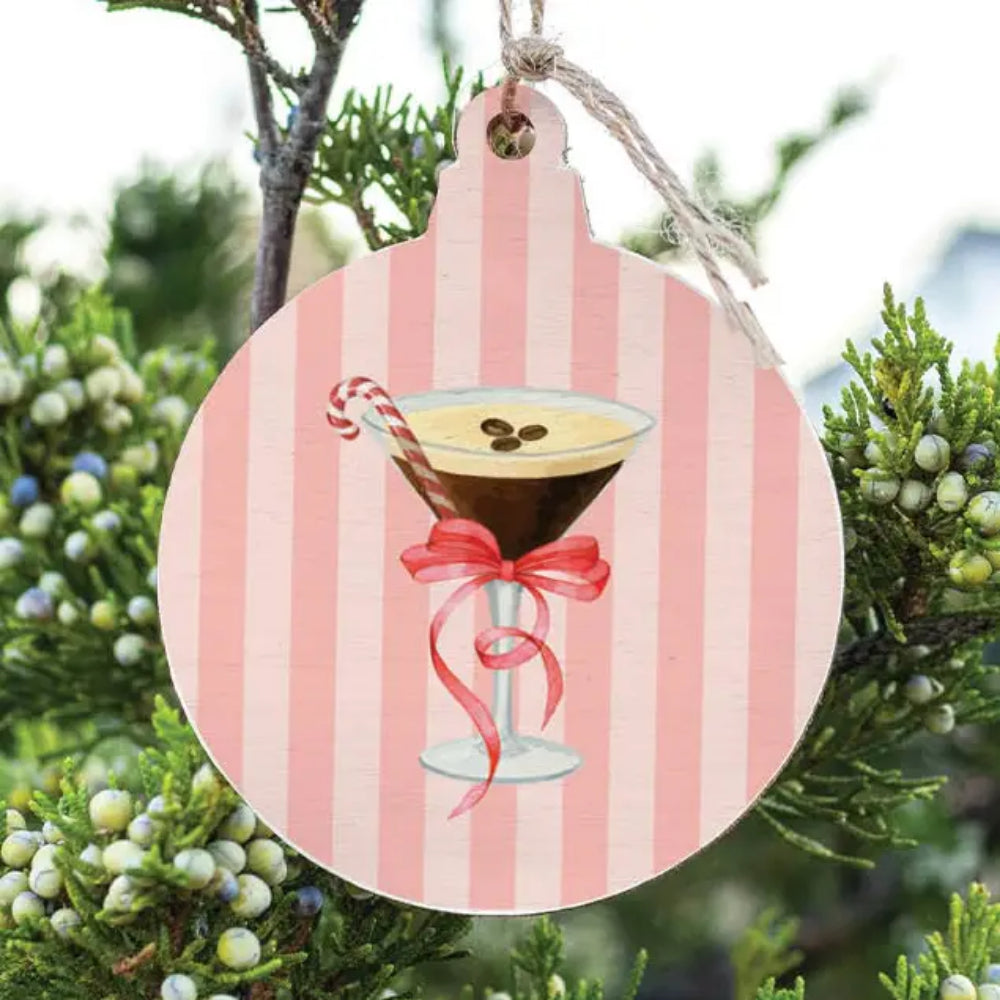 A ornament hanging outdoors with a martini design with pink stripe colors. 
