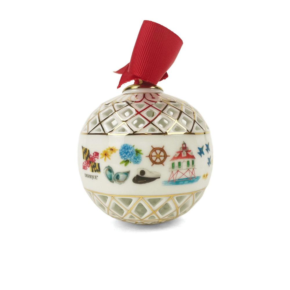 A decorative Christmas ornament shaped like a glass teapot with a red ribbon loop at the top. The ornament features a cream-colored body with gold lattice patterns on the upper and lower sections, and a central band decorated with colorful illustrations including a lighthouse, flowers, a whale, and a ship wheel.