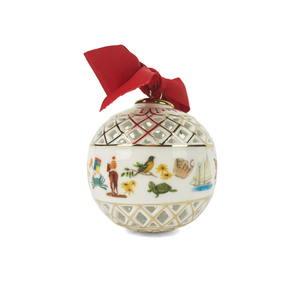 A decorative white Christmas ornament shaped like a globe, featuring gold lattice patterns, hand-painted coastal illustrations, and a red ribbon bow at the top, shown on a plain white background.