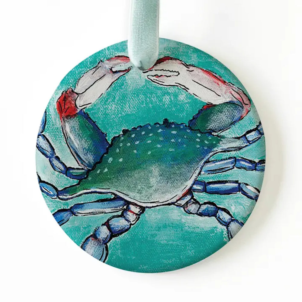 A round canvas wall hanging featuring a painted blue crab on a turquoise background, with a mint green hanging loop at the top.