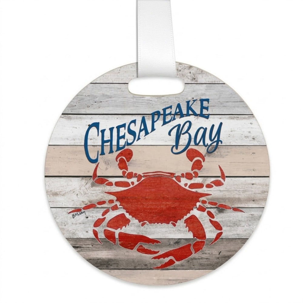 Round hanging ornament with a white hanging ribbon, featuring a red crab and the words 'Chesapeake Bay' in blue over a whitewashed wood plank background.