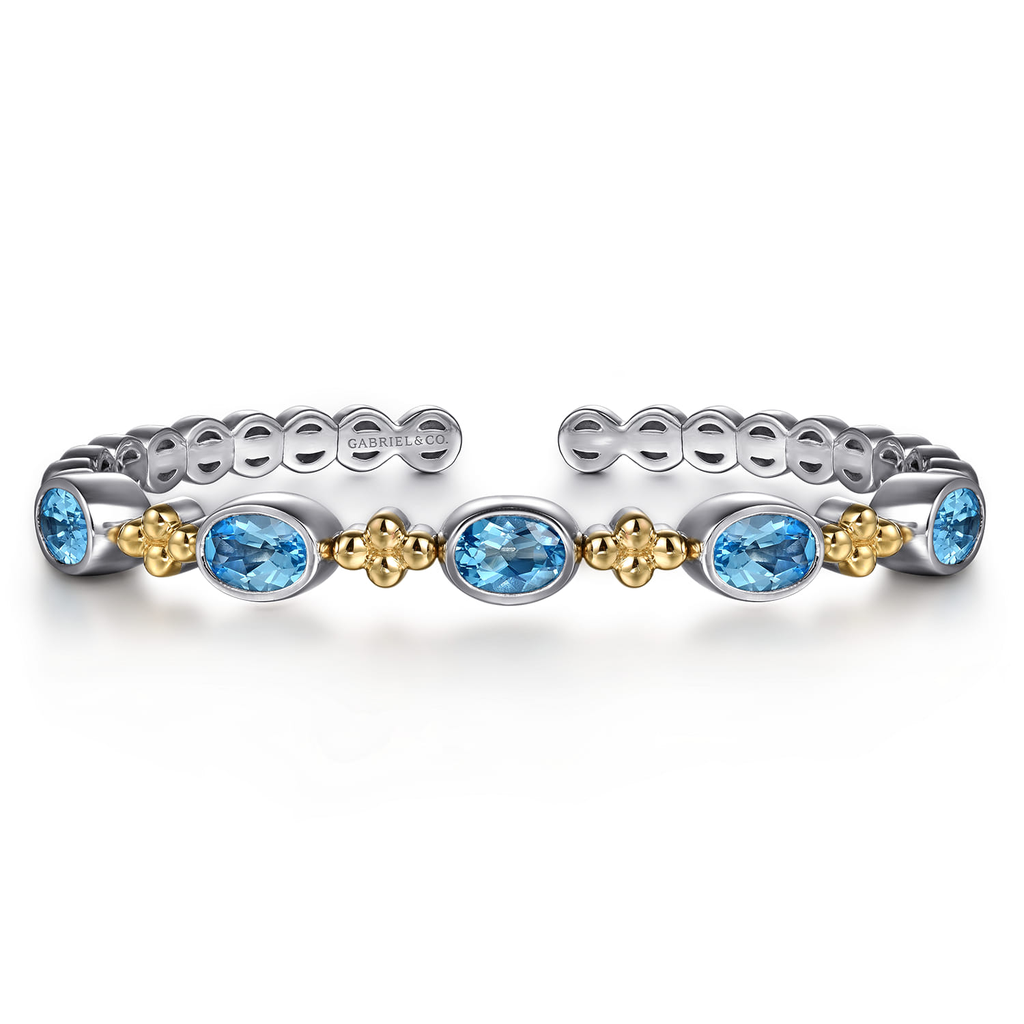 Two stackable rings with blue gemstones and gold accents on a white background