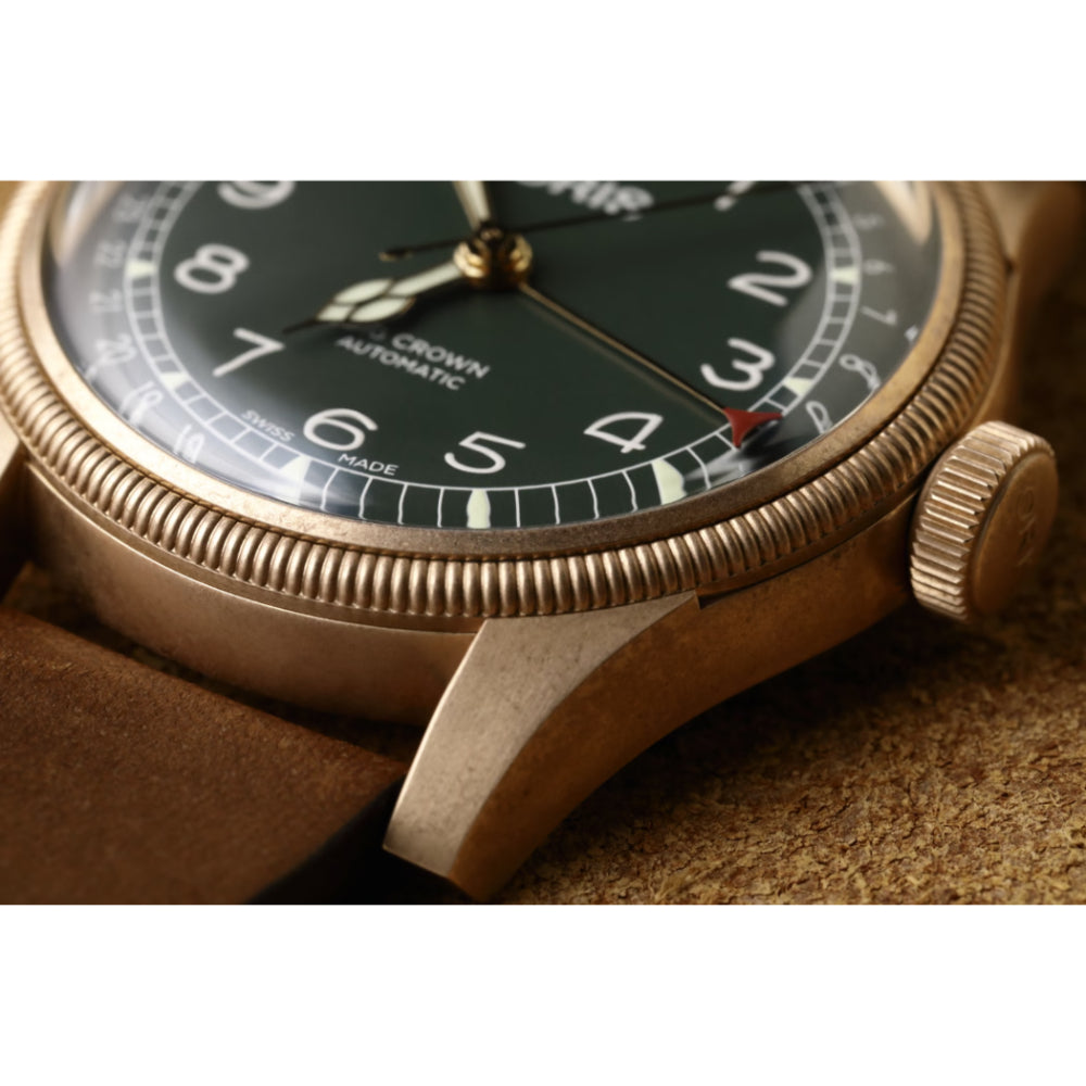 Close-up of a vintage-style watch with gold casing and black dial on a textured surface.