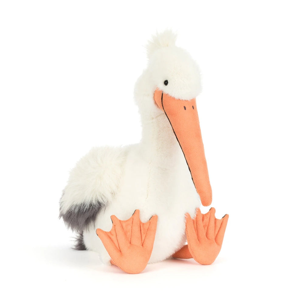A angled side photo of an Keli Pelican stuffed animal with a white and grey body and orange beek and legs on a white backround. 