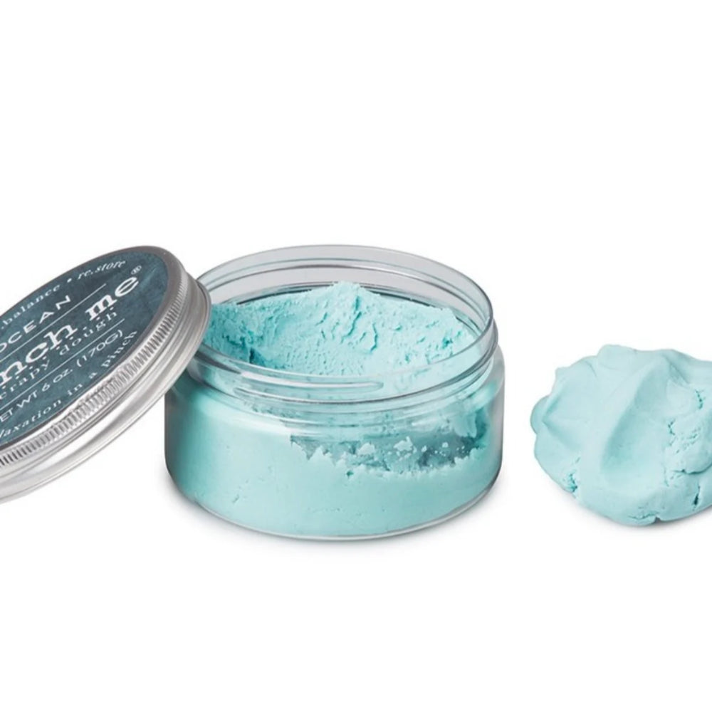 Open jar of blue ocean therapy dough on a white background.