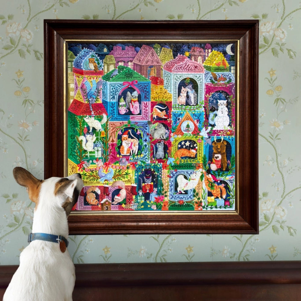 Framed colorful artwork of cats in various poses on a wall with a dog looking at it.