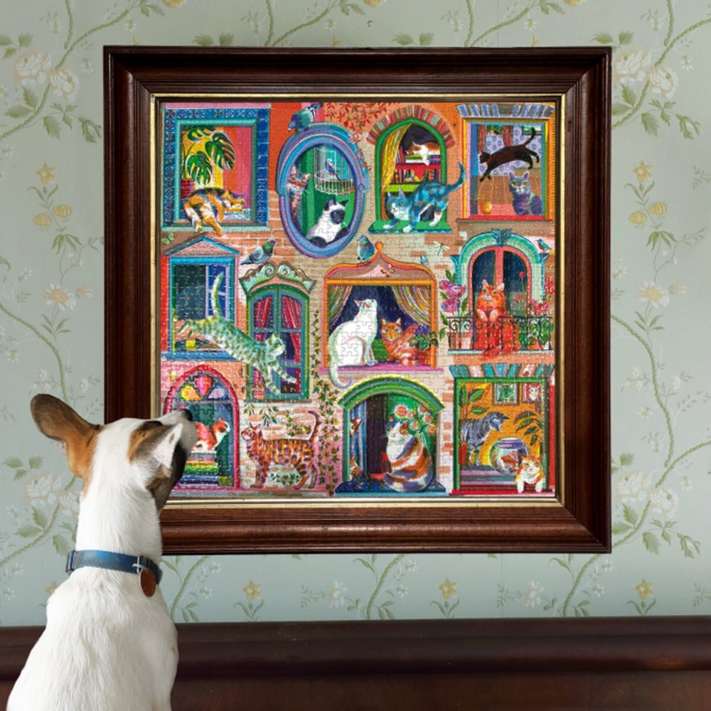 Dog looking at a colorful framed artwork of cats in various scenes on a wall.
