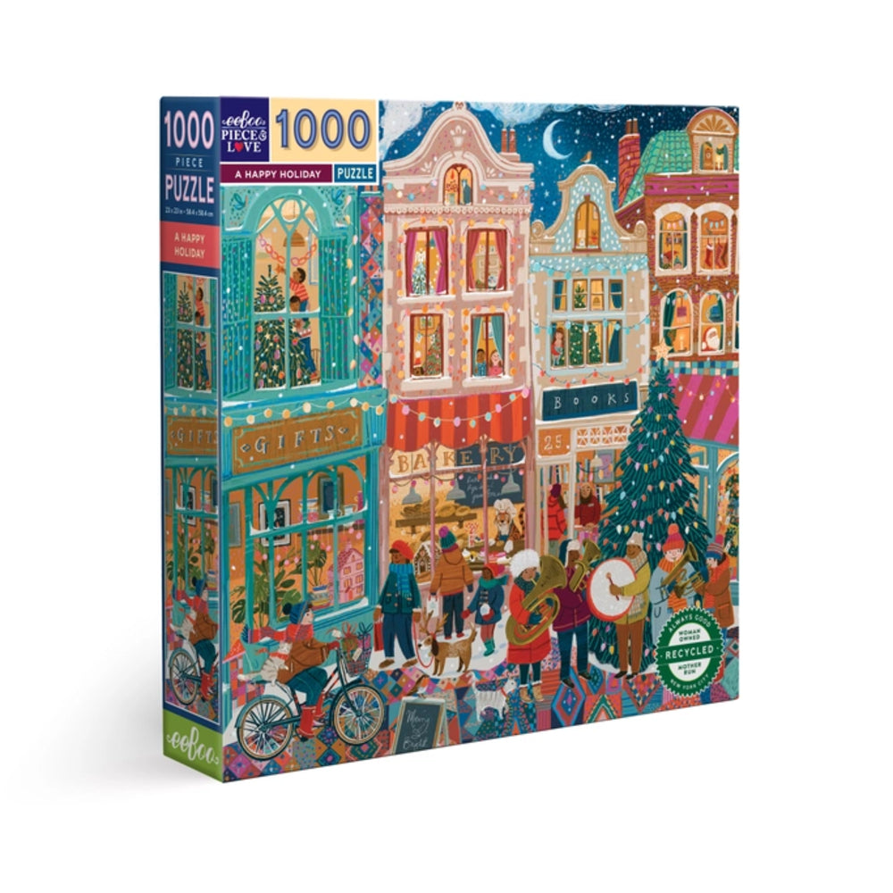 A 1000-piece jigsaw puzzle box featuring a colorful Christmas town street scene with decorated buildings, people, a tree, and festive storefronts. The box is shown at a slight angle on a clean white background.