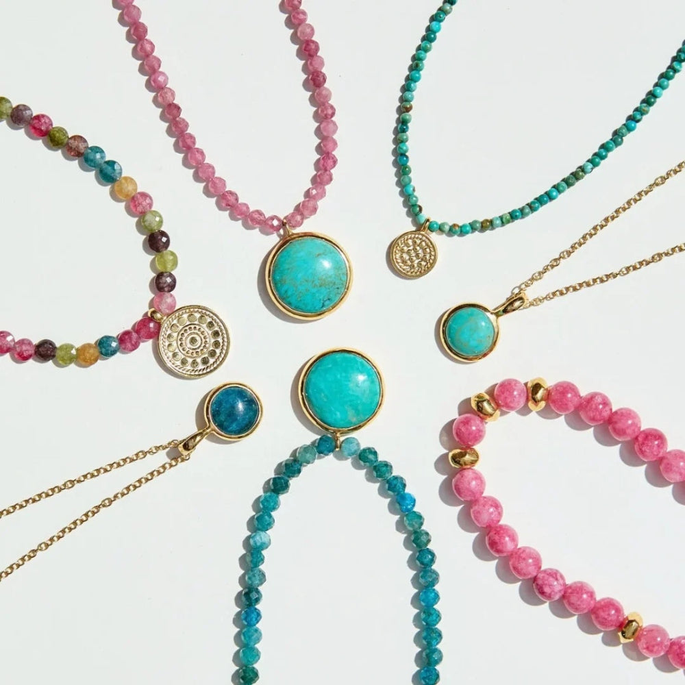 Six bohemian-style beaded necklaces and bracelets arranged in a circle on a white background. The jewelry features vibrant turquoise, pink, and teal beads with gold-toned chains and circular medallion pendants.