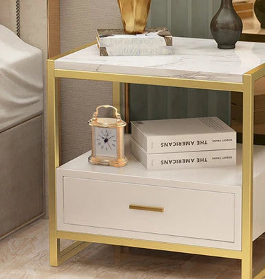 Modern side table with gold frame and marble top, featuring decorative items.