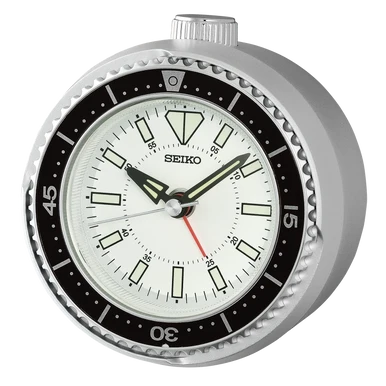 A Seiko analog alarm clock with a silver-toned metal casing, a black rotating bezel, and a white dial with black hands and a red second hand.