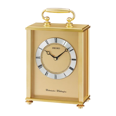 A Seiko Windsor-Whittington gold mantel clock with a rectangular gold case, clear glass front, Roman numeral hour markers, black hands, and a top handle, shown on a plain white background.