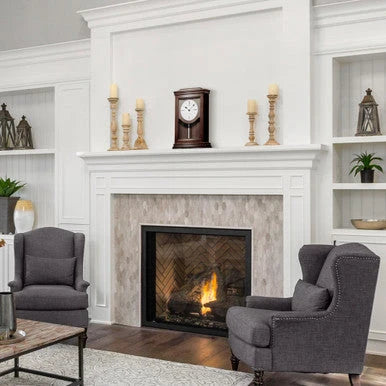 Living room with a fireplace, gray armchairs, and decorative items.