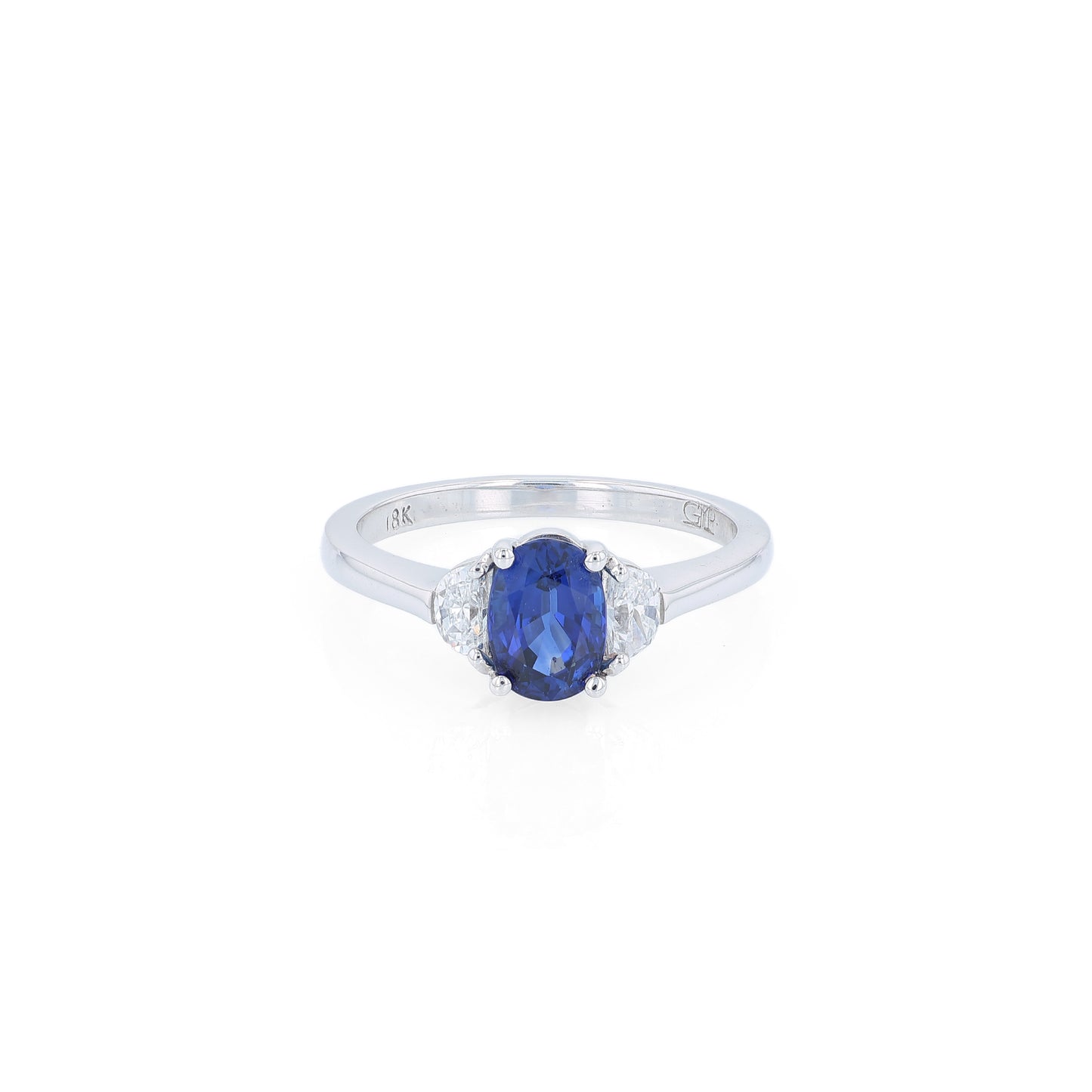 Platinum ring with an oval blue sapphire center and half moon cut diamond sides on a white background